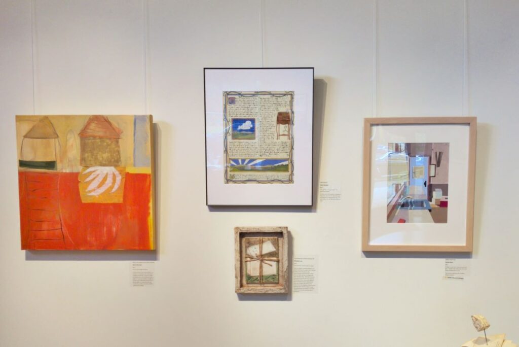 Photograph of a wall in a gallery, showing four artworks hanging on a white wall. The one at top center is "Attachment", the subject of this blog post, in a white mat and narrow black frame.