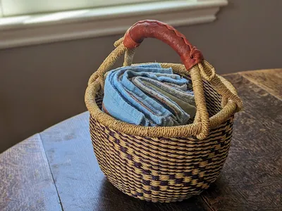 A collection of white and blue cotton dish towels sitting in a basket on top of a wooden table.