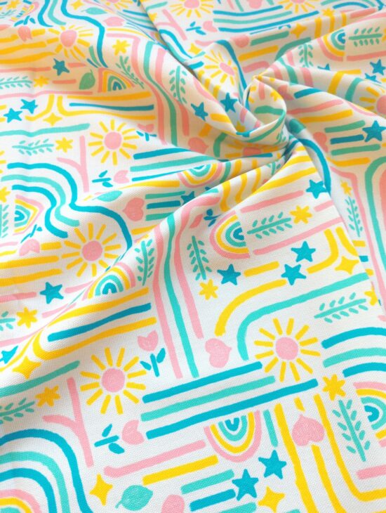 Canvas fabric with bright pink, yellow, blue, and green hand-drawn patterns scrunched up a little to show drape/weave.